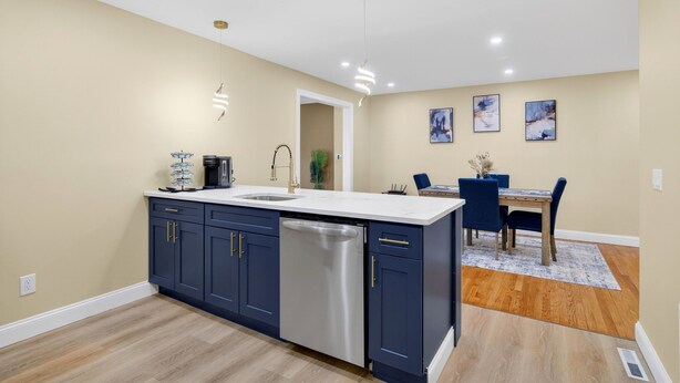 A modern kitchen with a central island, a dining area with a table and chairs, and a hallway leading to another room. - Perfect 4-bedroom house with AC in tranquil Albany (Albany)