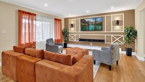 A living room with a large TV, a sofa set, and a fireplace. - Perfect 4-bedroom house with AC in tranquil Albany (Albany)