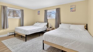 A bedroom with two beds, a nightstand, a lamp, and a window with curtains. - Perfect 4-bedroom house with AC in tranquil Albany (Albany)