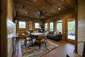 A wooden interior with a round table, sofa, and a ceiling fan. - Father & Son Built Cabin • Escape Room + Laser Tag • Sleeps 15 (Broken Bow)