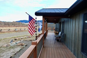 A wooden deck with outdoor seating, an American flag, and a view of mountains.