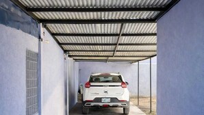 A covered parking area with a white SUV parked at the end.