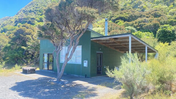 Un petit bâtiment d’un seul étage, à l’extérieur vert, doté d’un porche abrité et d’un arbre devant.