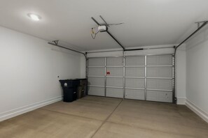 A garage with a ceiling fan, a light fixture, and a closed garage door. - Blue Desert Oasis - 4 Bed w/ Bonus Casita and Pool and Firepit (Goodyear)