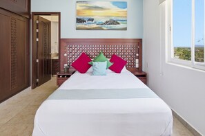 A hotel room with a bed, a headboard, a painting, and a window with a view.