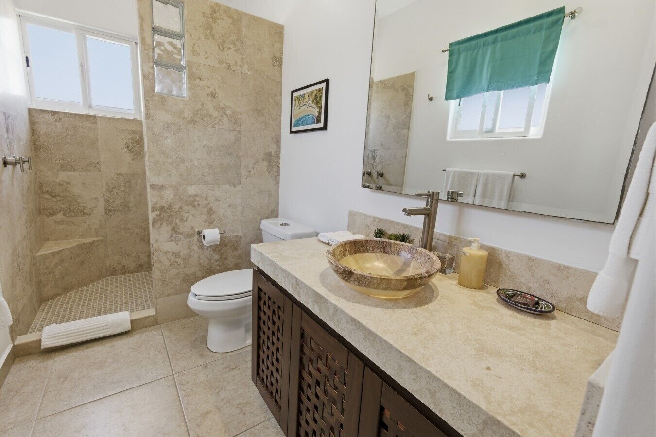 Une salle de bain avec un lavabo en pierre, des toilettes, une douche et un grand miroir.