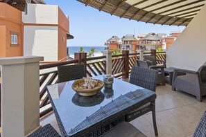 A balcony with a table, chairs, and a view of the ocean.