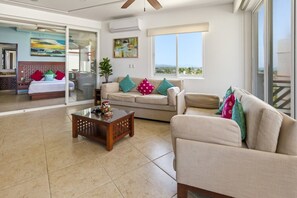 A spacious living area with a glass door leading to a balcony, a sofa set, a coffee table, and a painting on the wall. - 445 - Two Bedroom Ocean View (Bajos de Chila)