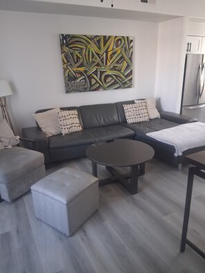 A modern living room with a grey sofa, a round coffee table, and a decorative abstract painting on the wall. - Stylish 1-bedroom with Resort Amenities located in Glendale (Glendale)