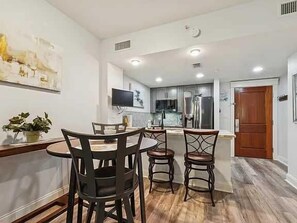 A modern kitchen with a dining area, a flat-screen TV, and a wooden door. - 1BR/1BA in Baytowne Wharf's Grand Sandestin (Miramar Beach)