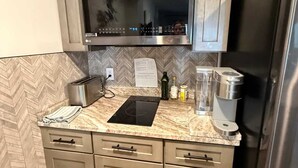 A kitchen with a microwave, toaster, coffee maker, and a herringbone-patterned backsplash. - 1BR/1BA in Baytowne Wharf's Grand Sandestin (Miramar Beach)