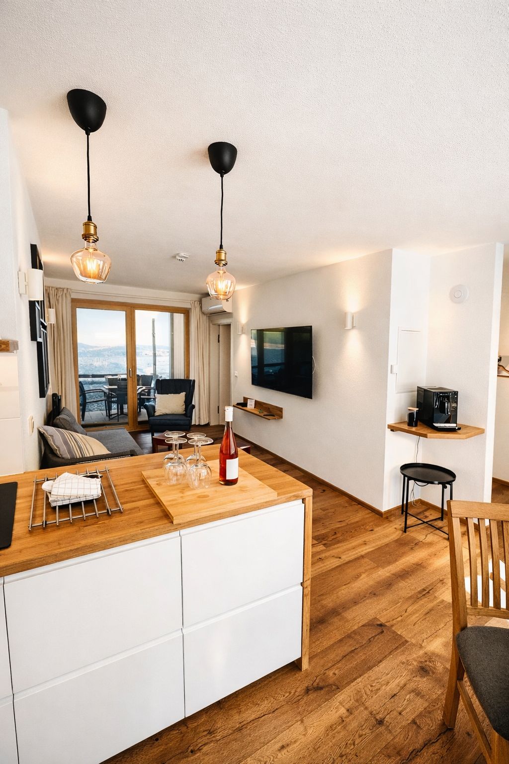 A modern living room with a large window, a flat-screen TV, and a wooden dining table.