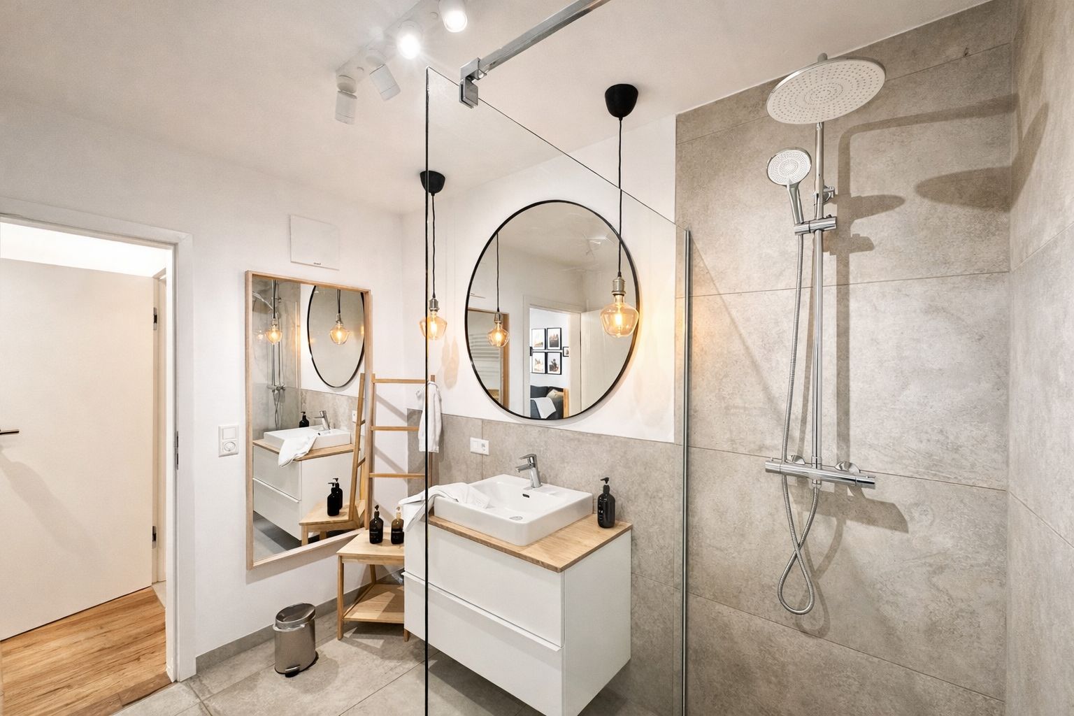 A modern bathroom with a large mirror, a shower, and a sink.