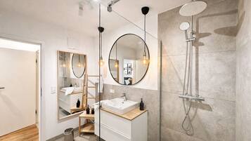 A modern bathroom with a large mirror, a shower, and a sink.