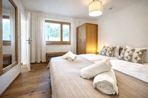 Ein Hotelzimmer mit einem Bett, einem Holzschrank, einer Bank und einem Fenster mit Vorhängen.
