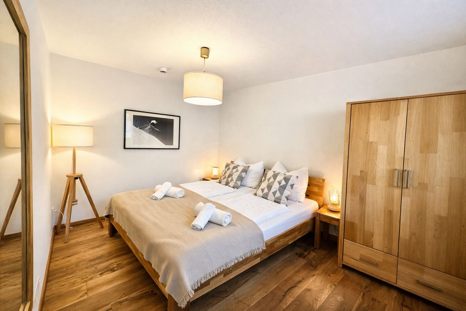 A hotel room with a bed, bedside lamps, a wardrobe, and a framed picture on the wall.