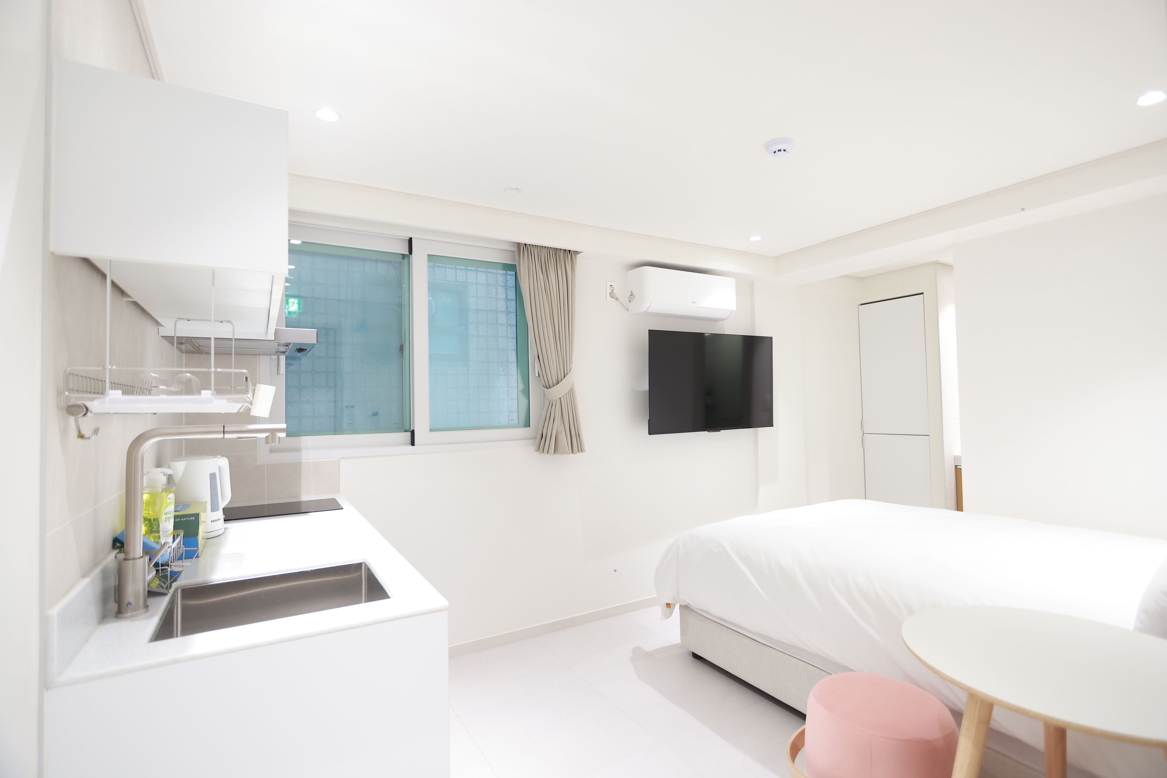 Une chambre d’hôtel moderne équipée d’un lit, d’une petite table, d’une télévision et d’une kitchenette.