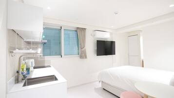 Une chambre d’hôtel moderne équipée d’un lit, d’une petite table, d’une télévision et d’une kitchenette.