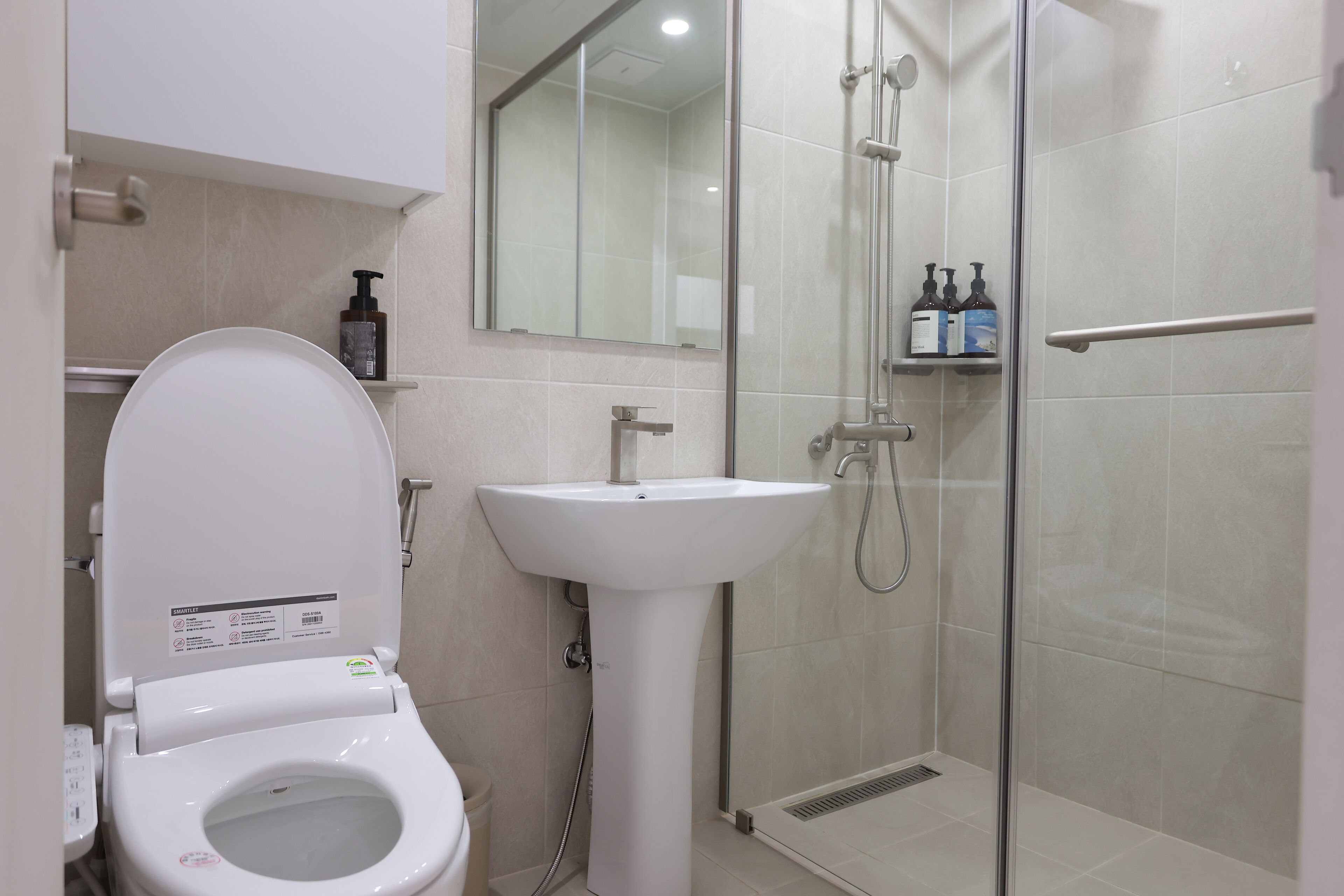 Un baño moderno con inodoro, lavabo y cabina de ducha de vidrio.