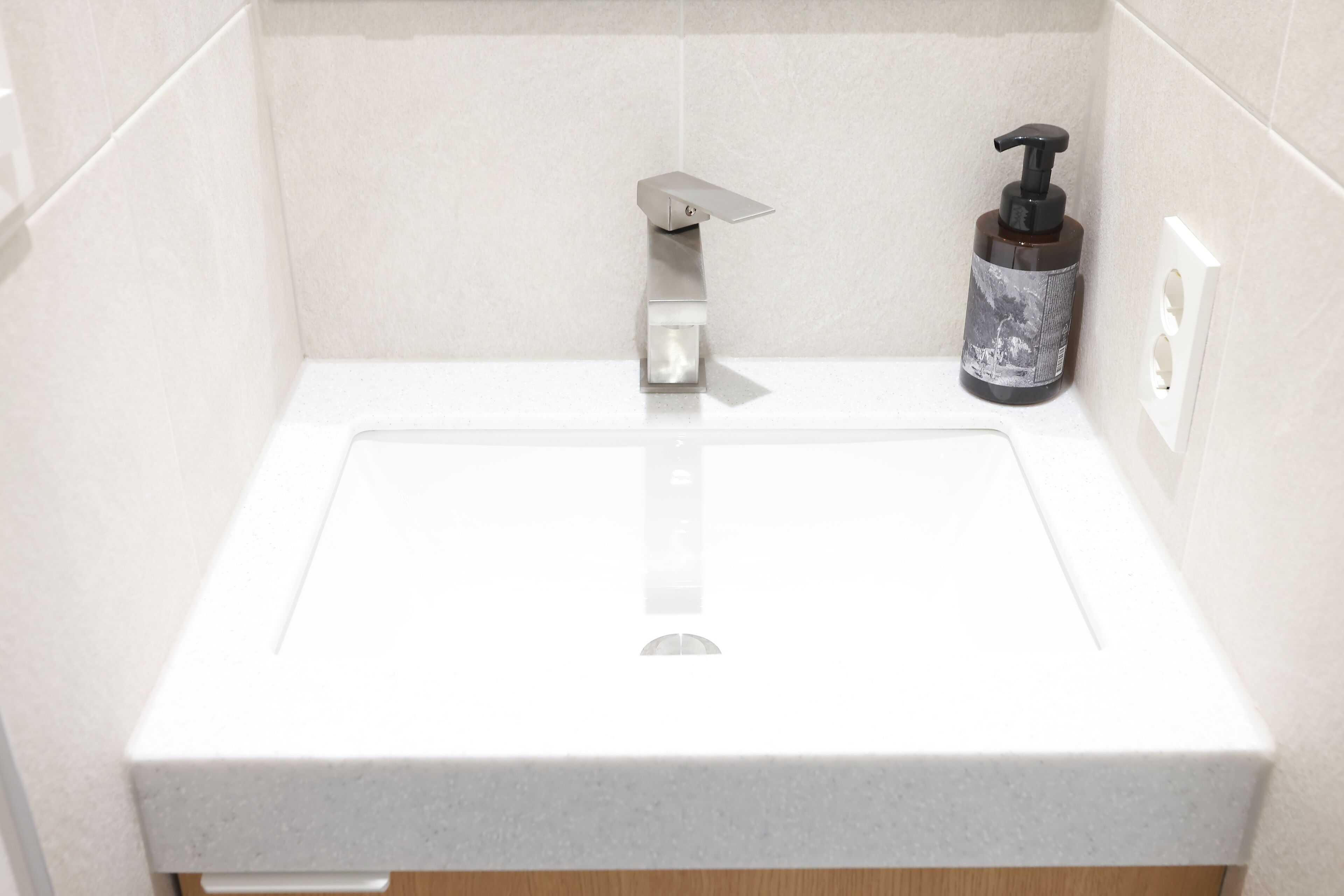 A bathroom with a white sink, a soap dispenser, and a towel rack.