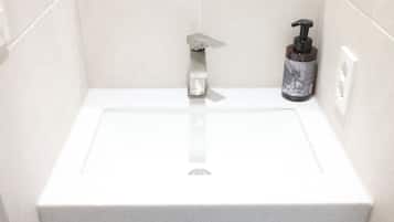 A bathroom with a white sink, a soap dispenser, and a towel rack.