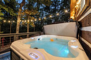 A hot tub on a balcony with a wooden railing, surrounded by trees and string lights. - Whiskey N Wine Ridge: Fire Pit, Hot Tub, Ample Parking, pets, near Pigeon Forge (Sevierville)
