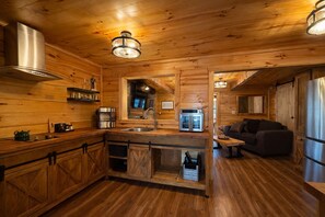 A wooden cabin interior with a kitchen, dining area, and a living room. - Whiskey N Wine Ridge: Fire Pit, Hot Tub, Ample Parking, pets, near Pigeon Forge (Sevierville)