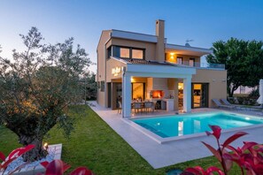 Une maison moderne dotée d’une piscine, d’un espace repas extérieur abrité et d’un jardin bien entretenu.