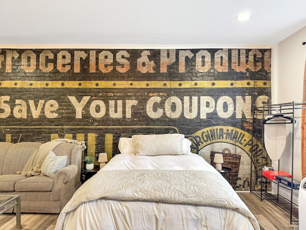 Un dormitorio con una cama, un sofá y un mural en la pared.