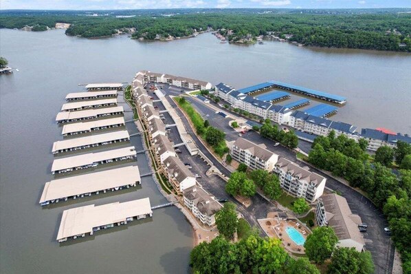 An aerial view of a waterfront hotel with multiple docked boats, a swimming pool, and a parking area. - Beach Area, 2 Pools, Pet-friendly Condo at 20.5mm (Osage Beach)