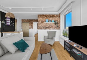 Una sala de estar moderna con sofá, sillón, mesa de centro, televisor y pared de ladrillo.
