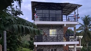 Un edificio di due piani con facciata in pietra, un balcone al piano superiore e un cartello con su scritto 'Bienvenidos a Residence XAMAN'.