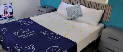 A bedroom with a bed, a nightstand, a TV, and a window.