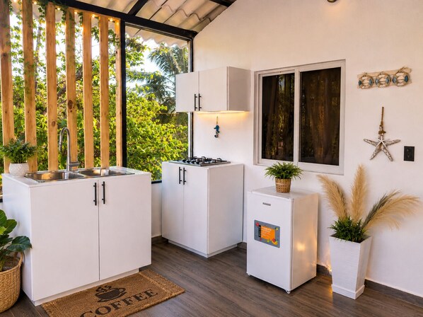 Une cuisine moderne avec des meubles blancs, une cuisinière encastrée et une fenêtre donnant sur un espace verdoyant.