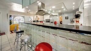 Eine moderne Küche mit Glasrückwand, Edelstahlgeräten und einer Bar mit Barhocker.