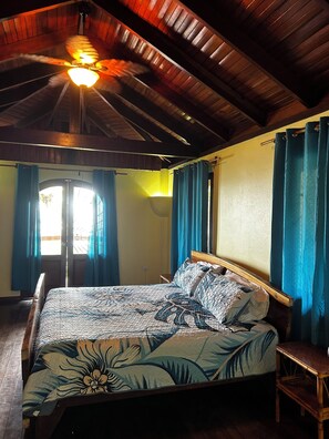 Une chambre à coucher avec un lit, un plafond en bois et des rideaux bleus.