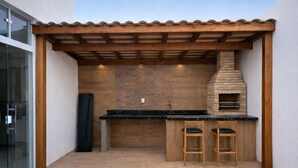 Una cucina esterna con forno a mattoni, sgabelli da bar in legno e una pergola.