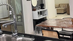 Una cucina moderna con lavello in acciaio inossidabile, una macchina per il caffè e un'area pranzo con tavolo e sedie.