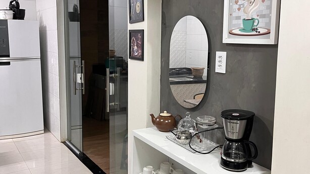 Una cucina moderna con frigorifero, macchina del caffè e ripiano con tazze.