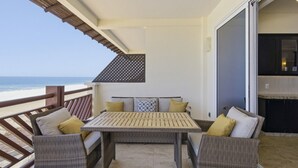 Ein Balkon mit Korbmöbeln, einem Tisch und Blick auf das Meer.