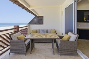 A balcony with wicker furniture, a table, and a view of the ocean. - 1452  Ocean Front 2 bedroom (Bajos de Chila)