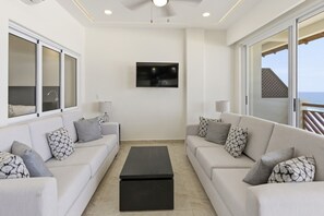 A modern living room with two sofas, a coffee table, a flat-screen TV, and large windows. - 1452  Ocean Front 2 bedroom (Bajos de Chila)