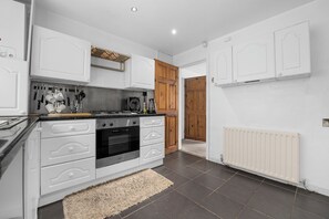 A modern kitchen with white cabinetry, a gas stove, and a built-in oven. - Cosy 2-Bed Flat in Middleton| Ideal for Work Stays (Middleton)