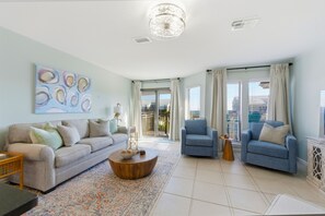 A living room with a sofa, armchairs, a coffee table, and a large window with curtains. - Ocean Mile K-6 ~ Salty Smiles! Offers unobstructed pool front and Gulf views! Newly renovated! (St. George Island)