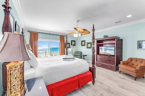 Un dormitorio con una cama grande, televisión, una silla y vistas al océano.