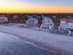 A beachfront property with multiple houses, some with balconies and large windows, situated on sandy terrain with a view of the ocean. - Isle Dream - a premier beachfront retreat in the gated Plantation community! (St. George Island)