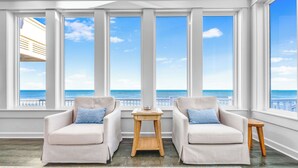 Ein Zimmer mit Meerblick, zwei Sofas, ein kleiner Holztisch und ein gemustertes Teppich.