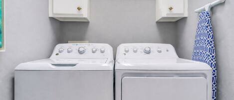 A laundry room with two white washing machines, a window above them, and a towel rack with a patterned towel.
