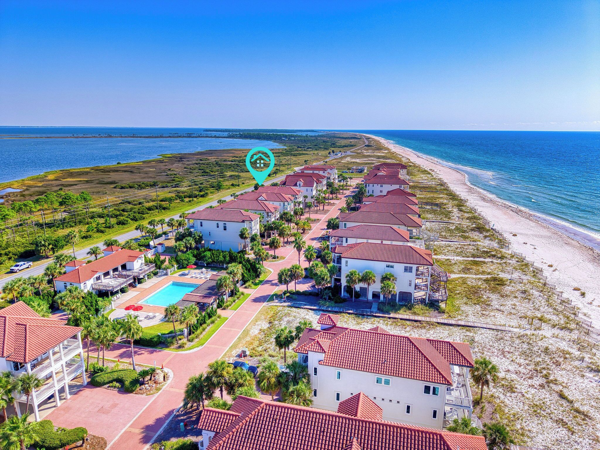 A coastal resort with multiple buildings, a swimming pool, and a beach.