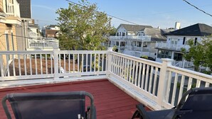 Ein Balkon mit zwei schwarzen Stühlen und einem kleinen weißen Tisch.
